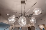 Stunning modern chandelier illuminates the open-concept kitchen and living area, creating a warm and inviting atmosphere.