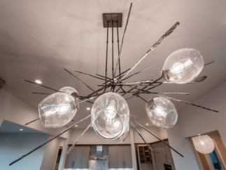 Stunning modern chandelier illuminates the open-concept kitchen and living area, creating a warm and inviting atmosphere.