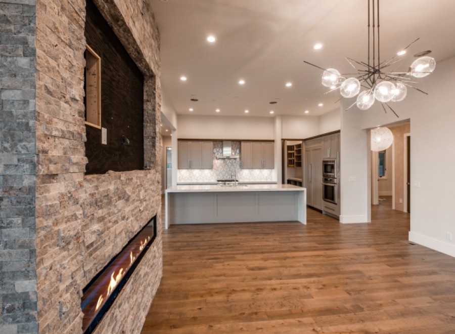 This stunning home boasts a modern kitchen with sleek cabinetry and high-end appliances, seamlessly flowing into a spacious living area with a unique stone fireplace feature.