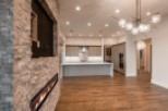 This stunning home boasts a modern kitchen with sleek cabinetry and high-end appliances, seamlessly flowing into a spacious living area with a unique stone fireplace feature.