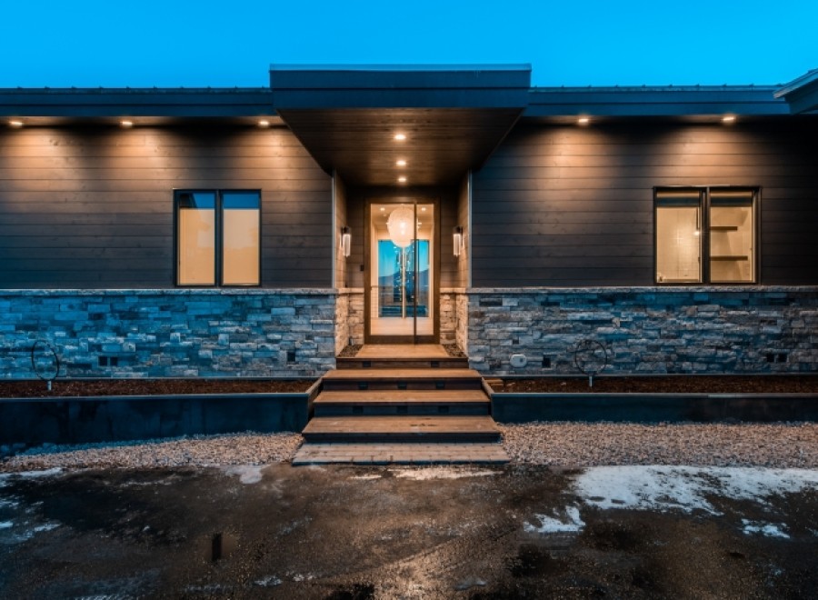This stunning modern home boasts a sleek exterior with dark siding, stone accents, and a welcoming entryway.