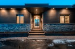This stunning modern home boasts a sleek exterior with dark siding, stone accents, and a welcoming entryway.