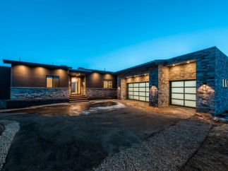 Stunning modern home with a large, attached garage featuring frosted glass garage doors.