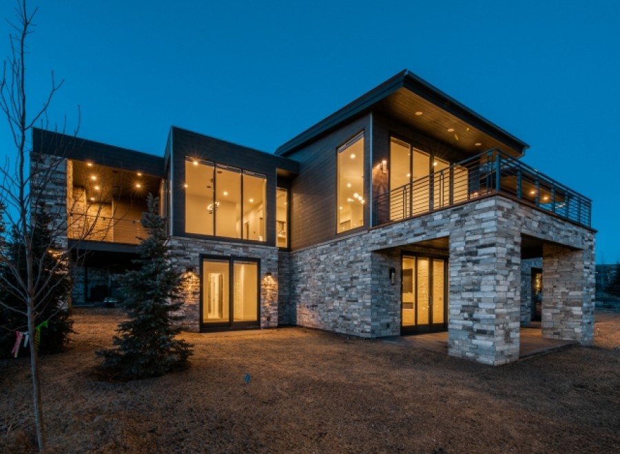 Stunning modern mountain home with expansive windows and a stone exterior.