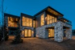 Stunning modern mountain home with expansive windows and a stone exterior.