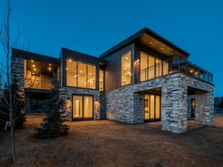 Stunning modern mountain home with expansive windows and a stone exterior.