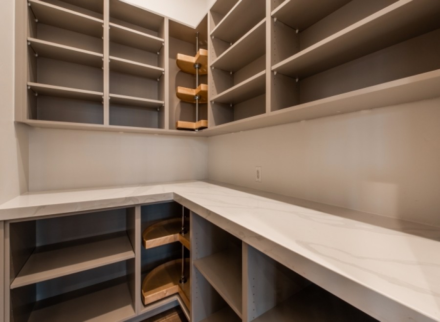 This stunning kitchen boasts ample storage with custom built-in shelves and pull-out corner drawers.