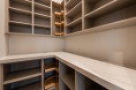 This stunning kitchen boasts ample storage with custom built-in shelves and pull-out corner drawers.