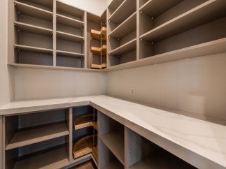 This stunning kitchen boasts ample storage with custom built-in shelves and pull-out corner drawers.
