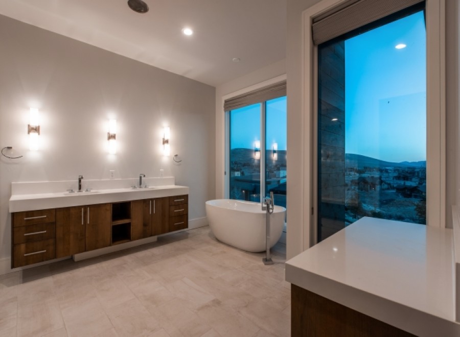 Luxurious master bathroom boasts a stunning view, double vanity with modern wood cabinets, and a freestanding soaking tub.