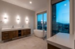 Luxurious master bathroom boasts a stunning view, double vanity with modern wood cabinets, and a freestanding soaking tub.