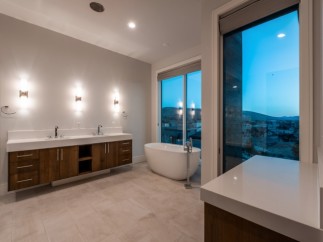 Luxurious master bathroom boasts a stunning view, double vanity with modern wood cabinets, and a freestanding soaking tub.