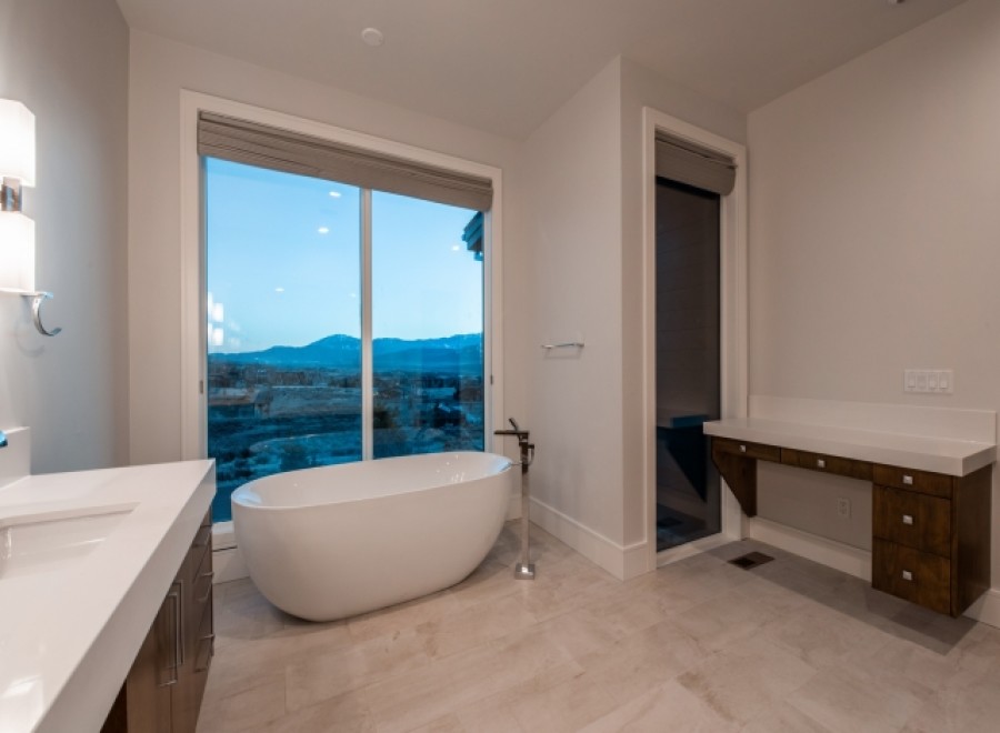 Luxurious bathroom boasts a freestanding tub and double vanity, offering breathtaking views through large windows.