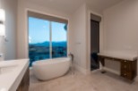 Luxurious bathroom boasts a freestanding tub and double vanity, offering breathtaking views through large windows.