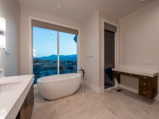 Luxurious bathroom boasts a freestanding tub and double vanity, offering breathtaking views through large windows.