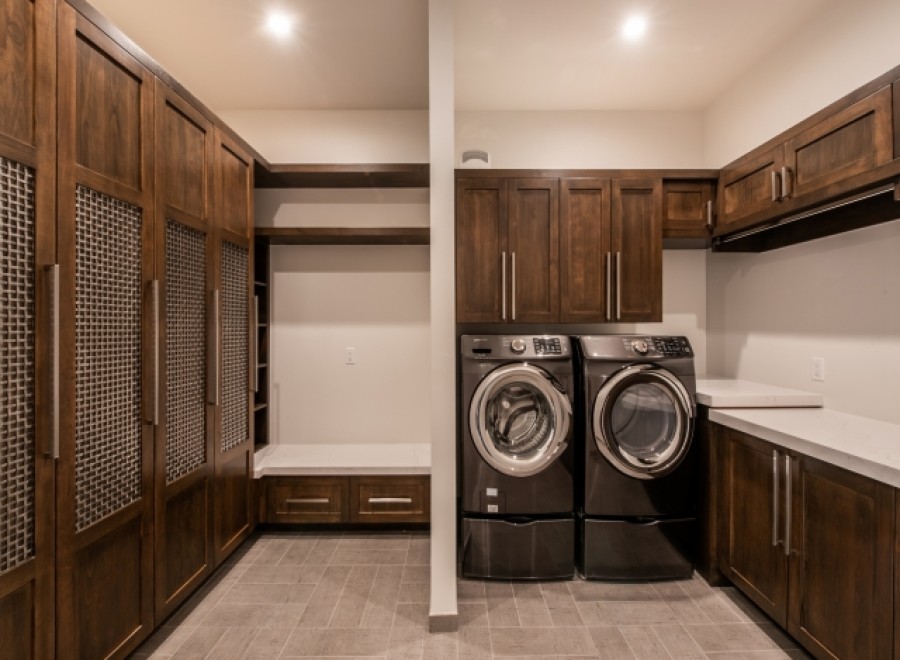This stunning laundry room boasts custom dark wood cabinetry, providing ample storage space.