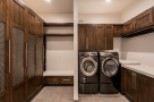 This stunning laundry room boasts custom dark wood cabinetry, providing ample storage space.