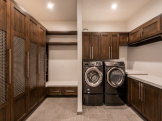 This stunning laundry room boasts custom dark wood cabinetry, providing ample storage space.