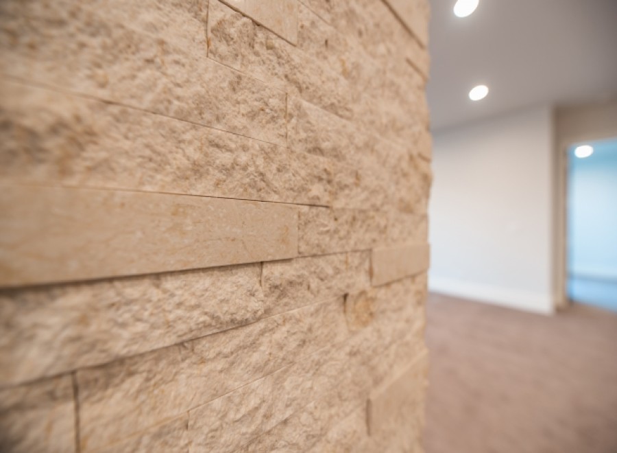 This stunning property boasts a unique interior design feature: a beautifully textured, light beige stone wall.