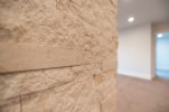 This stunning property boasts a unique interior design feature: a beautifully textured, light beige stone wall.