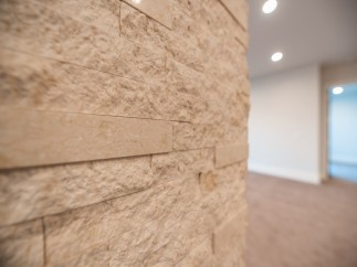 This stunning property boasts a unique interior design feature: a beautifully textured, light beige stone wall.