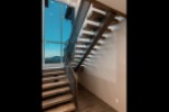 Modern staircase with sleek metal railing and rich wood treads, offering a stunning view through a large window.