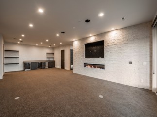 Stunning basement recreation room boasts a built-in bar, fireplace, and plush carpeting.
