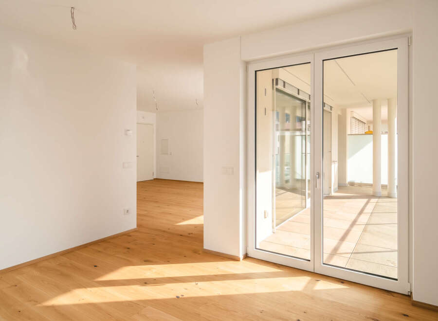 Step into this bright and airy modern apartment, featuring gleaming hardwood floors that catch the sunlight streaming through expansive glass doors.