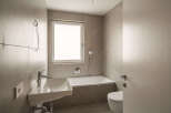 This modern bathroom features a sleek white sink with chrome fixtures, a spacious bathtub, and a wall-mounted toilet.