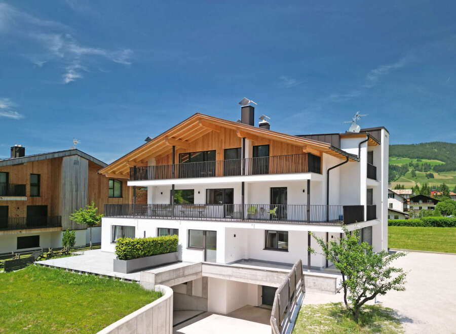 Experience modern alpine living in this stunning multi-story residence, featuring a striking wooden-beamed roof and expansive balconies perfect for enjoying the mountain views.