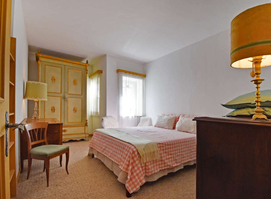 Step into this charming bedroom featuring a classic wooden wardrobe with ornate gold detailing, complemented by a vintage-style desk and chair.