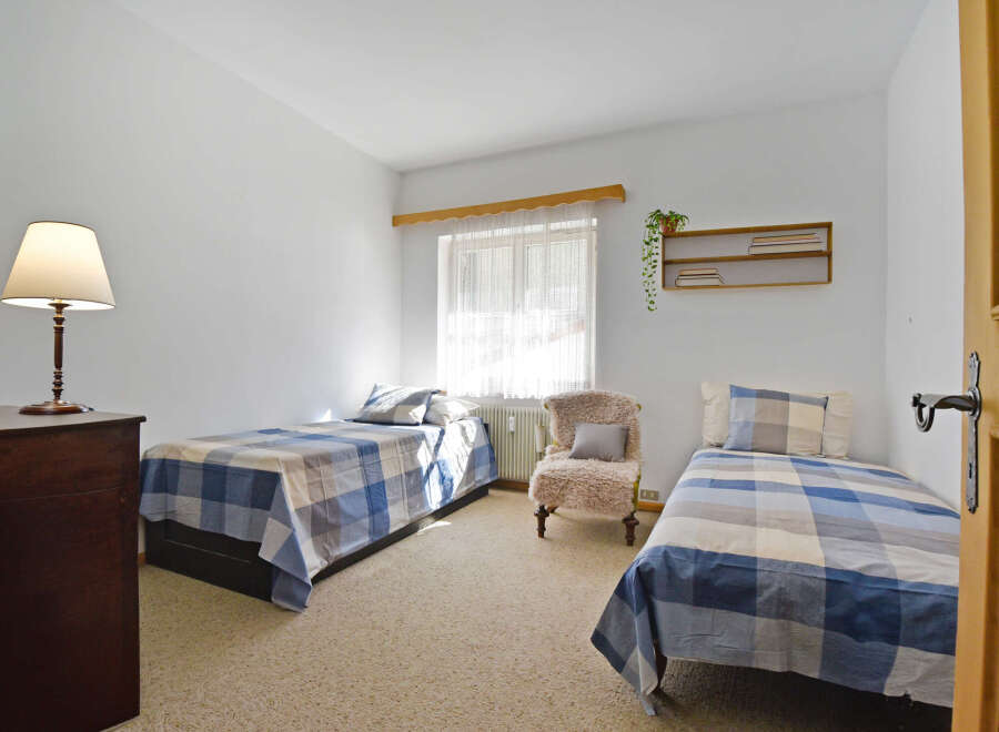 This charming bedroom features two twin beds, each adorned with blue and white plaid bedding, offering a cozy and inviting atmosphere.