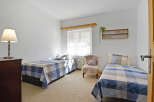 This charming bedroom features two twin beds, each adorned with blue and white plaid bedding, offering a cozy and inviting atmosphere.