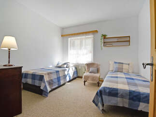 This charming bedroom features two twin beds, each adorned with blue and white plaid bedding, offering a cozy and inviting atmosphere.