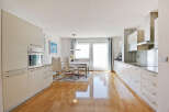 Experience modern living in this spacious kitchen and dining area, featuring sleek white cabinetry and a built-in oven.