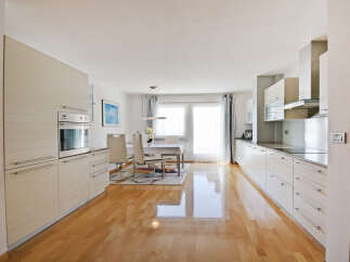 Experience modern living in this spacious kitchen and dining area, featuring sleek white cabinetry and a built-in oven.