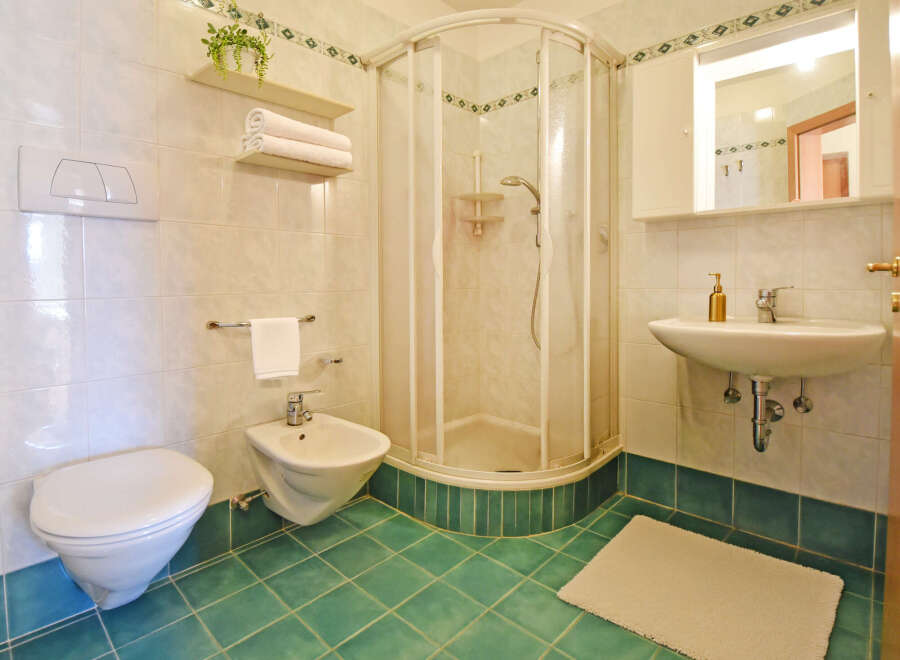 This bathroom features a modern toilet and bidet, complemented by a sleek corner shower enclosure.