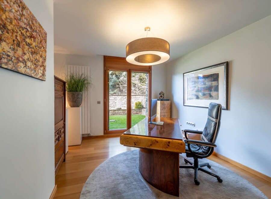 Step into this elegant home office, featuring a stunning wooden desk and a comfortable black leather chair.