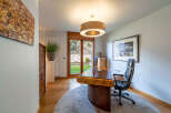 Step into this elegant home office, featuring a stunning wooden desk and a comfortable black leather chair.