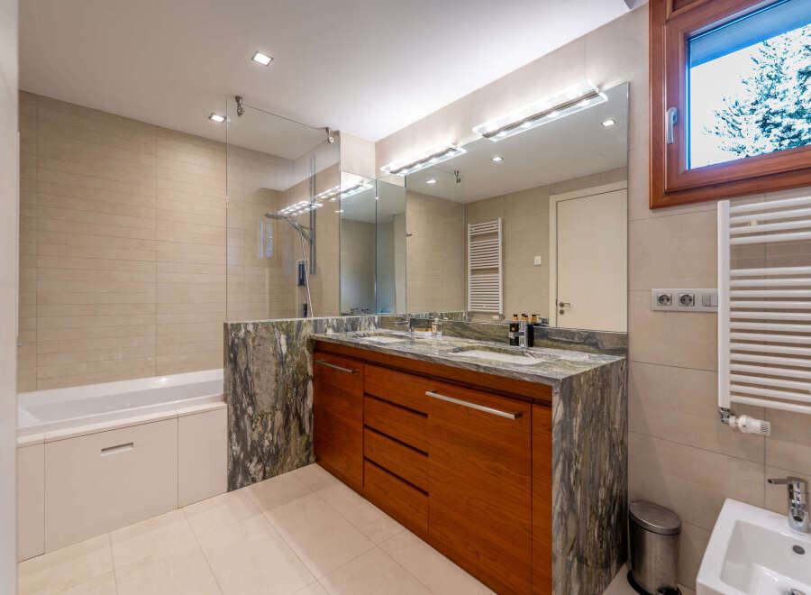 This luxurious bathroom features a stunning wooden vanity with a marble countertop, offering ample storage and a touch of elegance.