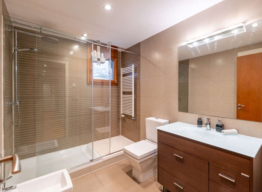 Step into this modern bathroom, featuring a sleek glass shower enclosure and a stylish vanity.