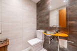 This modern bathroom features a unique design with a sleek, orange sink and a stylish mirror.
