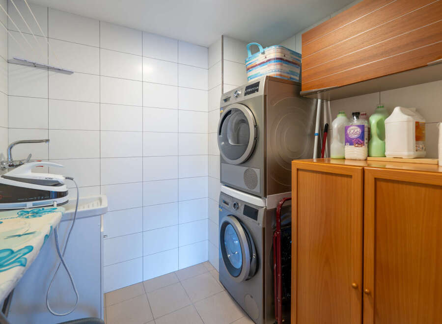 This laundry room features a modern design with a stacked washer and dryer, maximizing space efficiency.