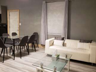 This modern living space boasts a sleek design with a comfortable white sofa and a glass-top coffee table.