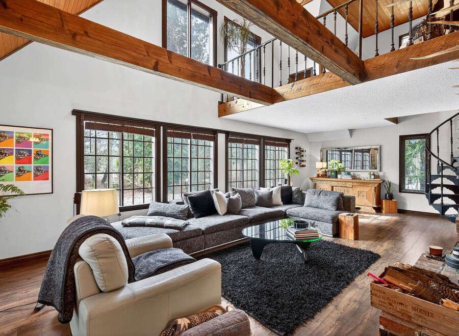 Step into luxury with this stunning property featuring a spacious living area with high ceilings and exposed wooden beams.