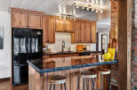 This stunning kitchen boasts custom wooden cabinetry, a sleek black countertop, and a stylish breakfast bar.
