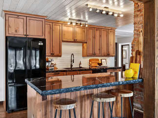 This stunning kitchen boasts custom wooden cabinetry, a sleek black countertop, and a stylish breakfast bar.