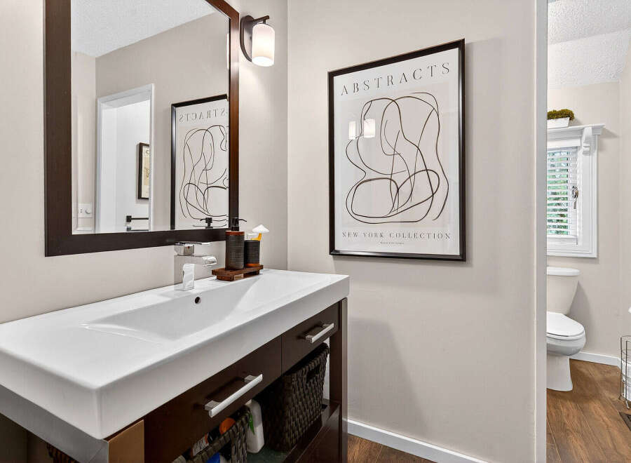 This modern bathroom boasts a sleek design with a stylish vanity and a contemporary abstract art piece.