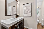 This modern bathroom boasts a sleek design with a stylish vanity and a contemporary abstract art piece.