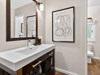 This modern bathroom boasts a sleek design with a stylish vanity and a contemporary abstract art piece.